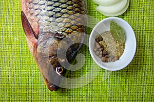 Fresh fish, sliced onion and spices on kitchen napkin. Raw carp with peppers and onions. River fish