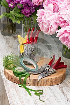 Fresh flowers, leaves, and tools to create a bouquet on a table, florist`s workplace