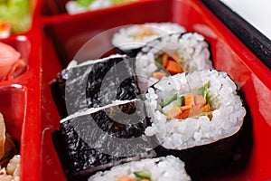 Fresh food portion in japanese bento box with salad, main course. Sushi roll with vegetables. Vegetarian dish.