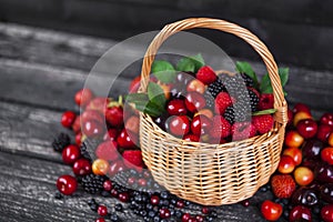 Fresh forest berries in basket on wooden table. Copy space