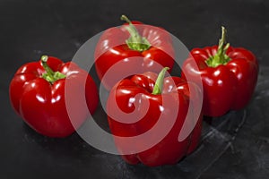 Fresh four red peppers on a black background in the center of the frame