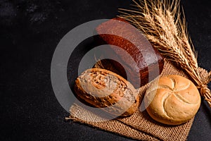 Fresh fragrant bread with grains and cones of wheat against a dark background