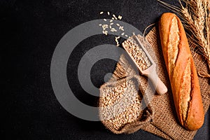 Fresh fragrant bread with grains and cones of wheat against a dark background