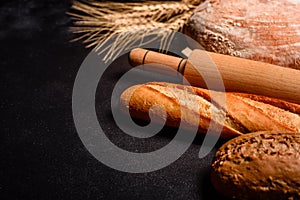 Fresh fragrant bread with grains and cones of wheat against a dark background