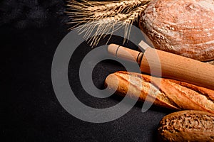 Fresh fragrant bread with grains and cones of wheat against a dark background