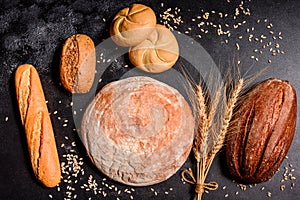 Fresh fragrant bread with grains and cones of wheat against a dark background