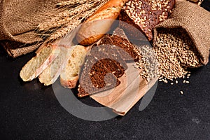 Fresh fragrant bread with grains and cones of wheat against a dark background