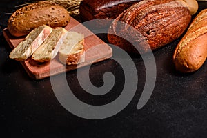 Fresh fragrant bread with grains and cones of wheat against a dark background