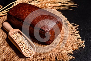 Fresh fragrant bread with grains and cones of wheat against a dark background