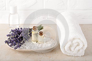 Fresh fragrant lavender and lavender essential oil on a cosmetic bath salt near white terry towel in a bathroom. Home made spa,