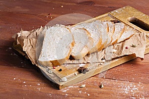 Fresh and fragrant white bread is sliced and lies on a wooden ba