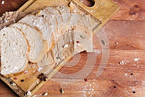 Fresh and fragrant white bread is sliced and lies on a wooden ba