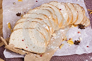 Fresh and fragrant white bread is sliced and lies on a wooden ba