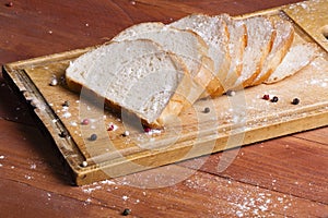 Fresh and fragrant white bread is sliced and lying on a wooden b