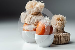 Fresh free range eggs with natural feathers in egg cups, eggs in woolen caps