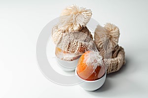 Fresh free range eggs with natural feathers in egg cups, eggs in woolen caps