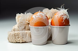 Fresh free range eggs with natural feathers in egg cups, eggs in woolen caps