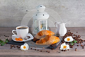 Fresh french buttery croissants for breakfast with cup of aroma coffee and candlestick lamp. Good start for day.