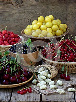 Fresh fruit and berries in baskets on wooden background