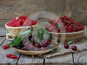Fresh fruit and berries in baskets on wooden background