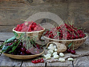 Fresh fruit and berries in baskets on wooden background