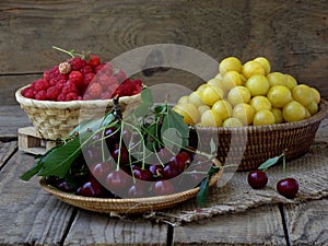Fresh fruit and berries in baskets on wooden background