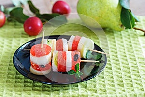 fresh fruit canape in a black plate on a green napkin