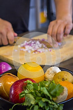 Fresh fruit in the kitchen with chef cutting onion to prepare food