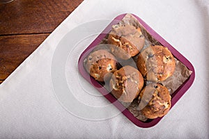 Fresh fruit muffin or cake with raisins in the bowl on the wooden brown table background and linen towel, rag, the cloth. Side vi
