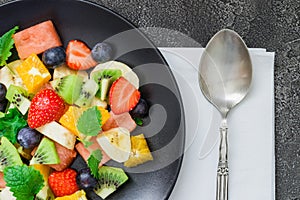 Fresh fruit salad on black plate. Top view