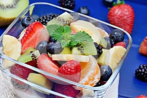 Fresh fruit salad in a bowl on blue wooden table
