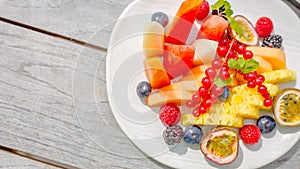 Fresh fruit salad, top view in a bowl on wooden background, vegetarian food concept