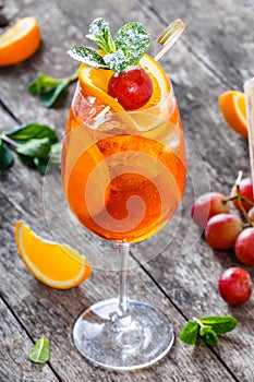 Fresh fruit tropic cocktail with mint, orange and grapes in tall glass on wooden background. Summer drinks and alcoholic cocktails