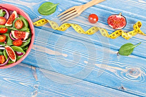 Fresh fruit and vegetable salad, fork with tape measure, slimming and nutrition concept, copy space for text