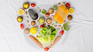 Fresh fruit and vegetables, grains, and nuts on a white background in shape of heart.