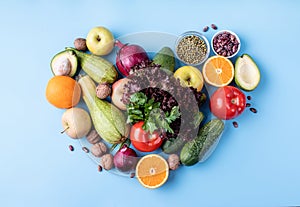 Fresh fruit and vegetables in heart shape top view flat lay on blue background