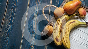 Fresh fruit on a white wooden tray: banatas, pears, apricots. Countryside setting. Top view.