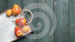 Fresh fruit on a white wooden tray: banatas, pears, apricots. Countryside setting. Top view.