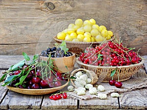 Fresh fruits and berries in the basket on wooden background