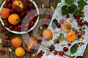 Fresh fruits and berries on wooden background. Ripe sweet cherry, currants, peach and apricot, mulberry on the kitchen table.