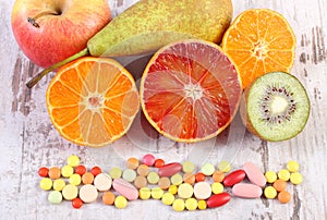 Fresh fruits and colorful medical pills, choice between healthy nutrition and medical supplements