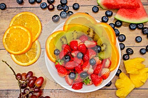 Fresh fruits concept, Tropical fruits and assorted berry salad in bowl on wooden background