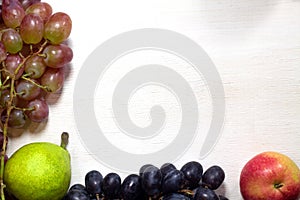 Fresh fruits grapes, pear and apple on wooden boards frame background.