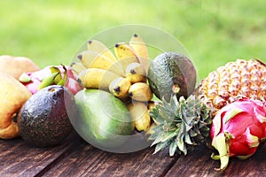 Mixed exotic fruits on wood background. Healthy eating, dieting. Top view with grass copy space