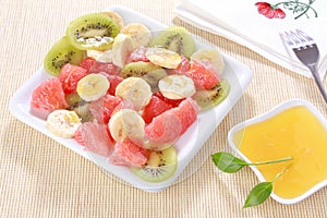 Fresh fruits salad on white plate with honey