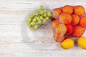 Fresh fruits on the table. Oranges, lemons, grapes in retail packaging. Flat lay.