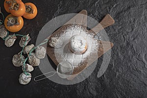 Fresh fuyu and dried persimmon fruits on black background