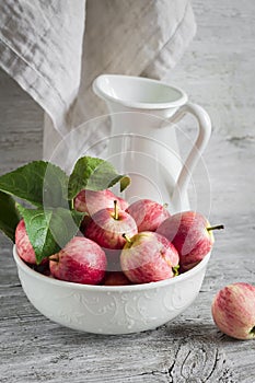 Fresh garden apples in a white bowl, vintage enameled pitcher