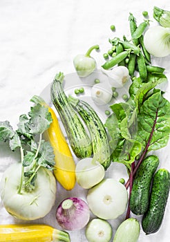 Fresh garden seasonal vegetables - kohlrabi, zucchini, squash, cucumbers, chard, green peas, onions, garlic on a light background,