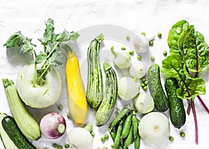 Fresh garden seasonal vegetables - kohlrabi, zucchini, squash, cucumbers, chard, green peas, onions, garlic on a light background,